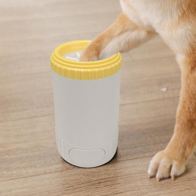 White dog paw cleaning cup with yellow lid on a wooden floor next to a dog's paw