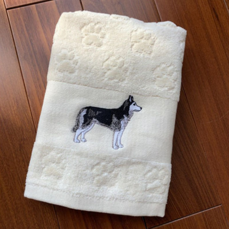 White towel with embroidered dog design on a wooden floor
