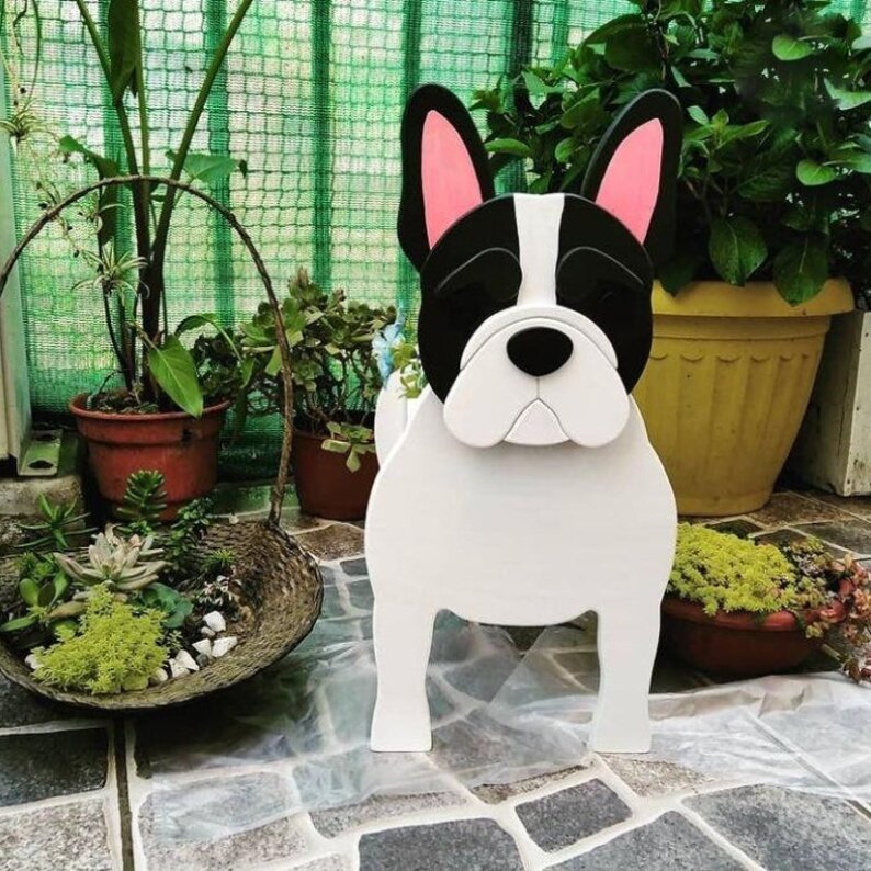 White and black dog-shaped decorative item on a stone surface with plants in the background