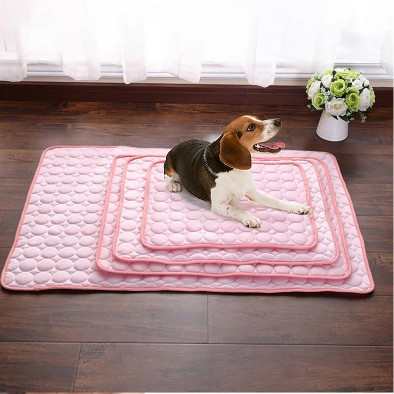 Dog lying on a pink quilted self-cooling mat in a room with a vase of flowers.