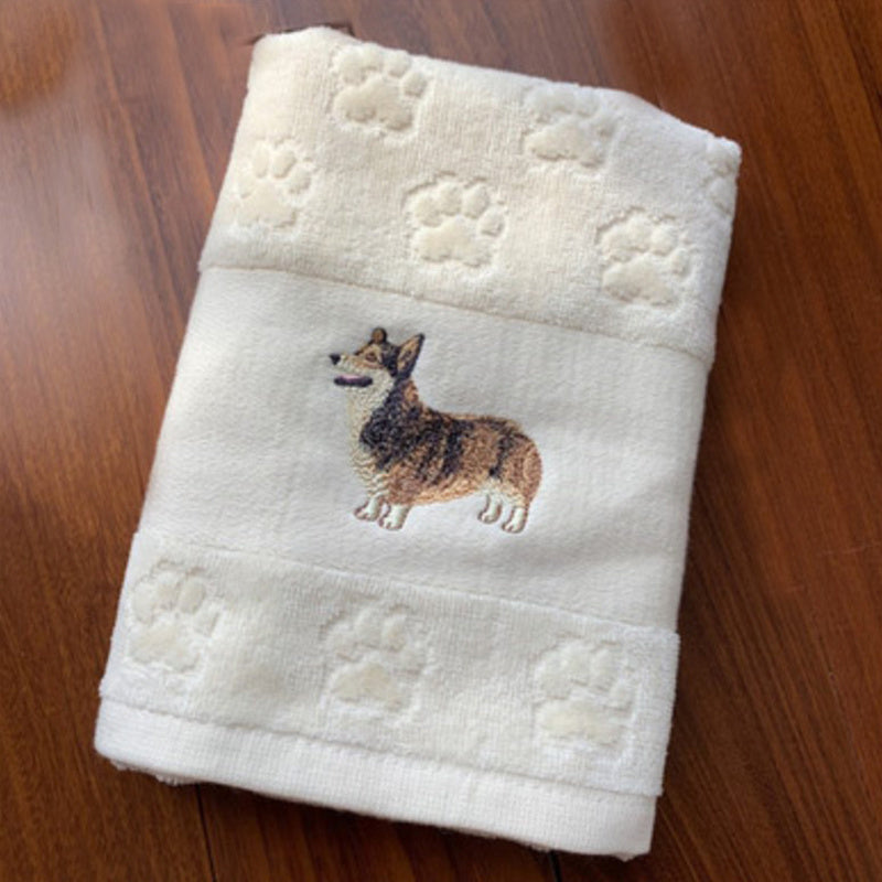 Folded towel with embroidered dog design on a wooden surface