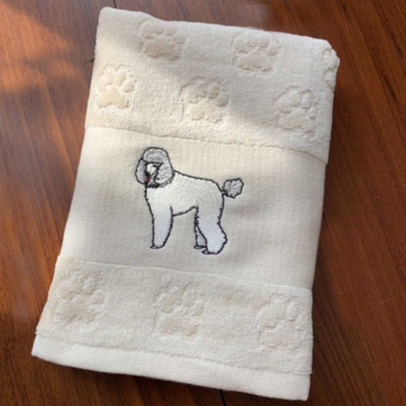 Beige towel with embroidered poodle design on a wooden surface