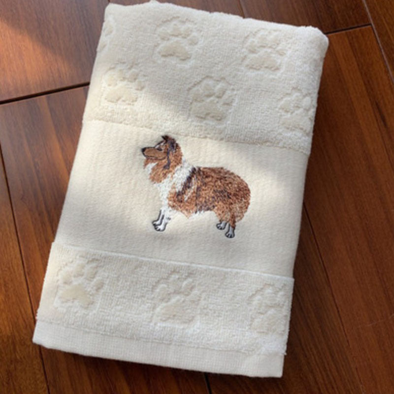 Folded towel with embroidered dog design on a wooden surface