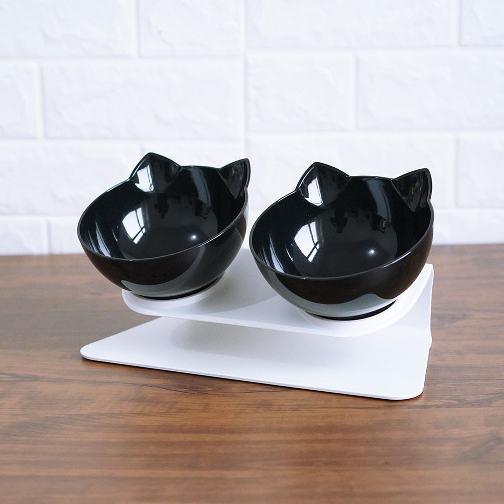 Black cat-shaped bowls on a white stand against a white tiled wall.
