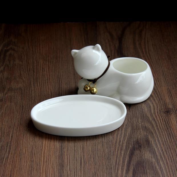 White ceramic cat-shaped container with a lid on a wooden surface