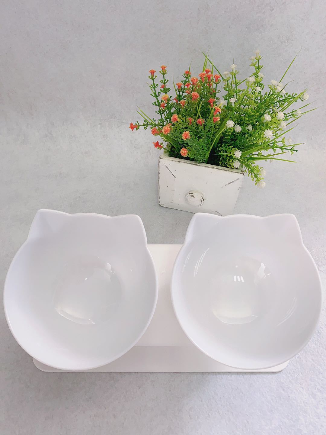 White double pet bowl with a small plant on a gray background