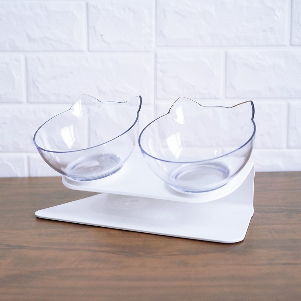 Cat-shaped clear bowls on a white stand against a white tiled wall.