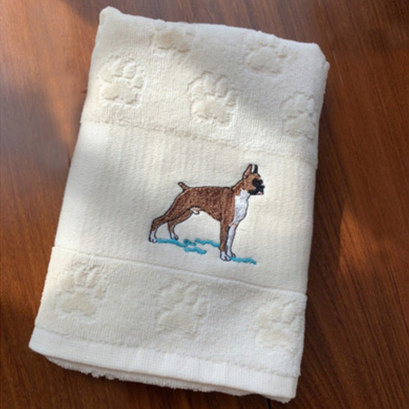 Folded towel with an embroidered dog design on a wooden surface
