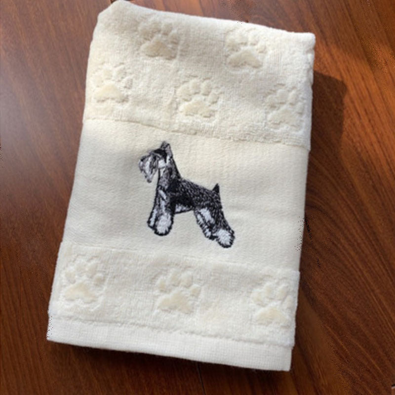 White towel with embroidered dog design on a wooden surface