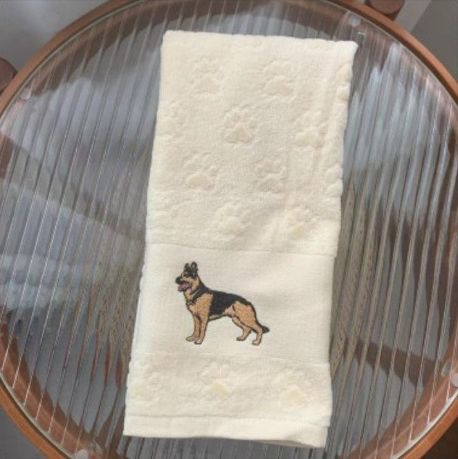 White towel with embroidered dog design on a glass surface