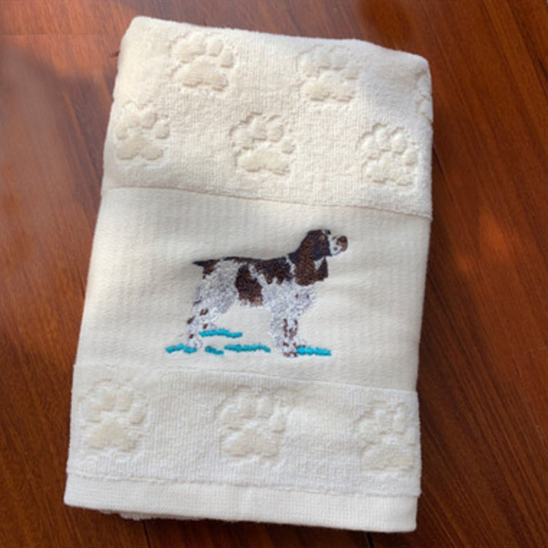White towel with embroidered dog design on a wooden surface