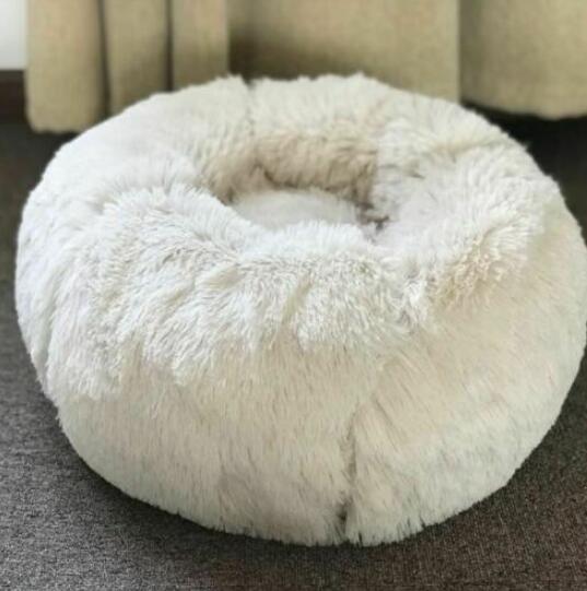 Fluffy white pet bed on a carpeted floor with a blurred background