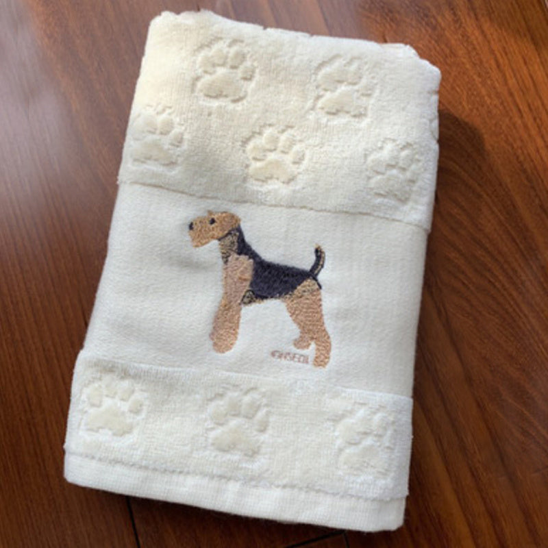 Folded towel with embroidered dog design on a wooden surface