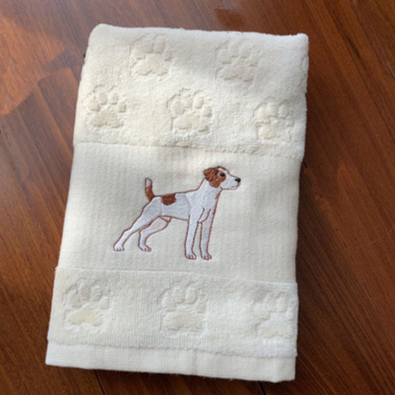 Folded towel with an embroidered dog design on a wooden surface