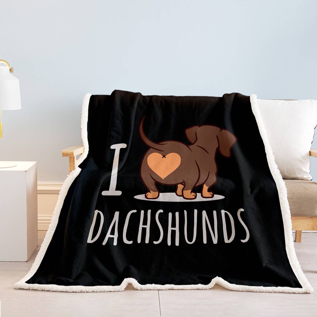 Black blanket with a dachshund design and 'I love dachshunds' text on a couch.