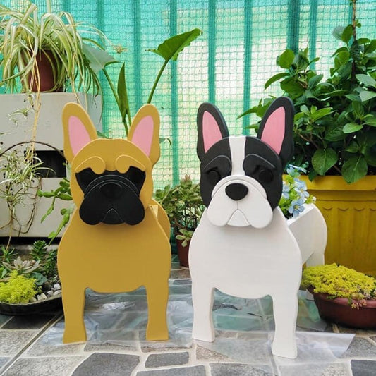 Two dog-shaped planters, one yellow and one white, in a garden setting with plants and a green fence.