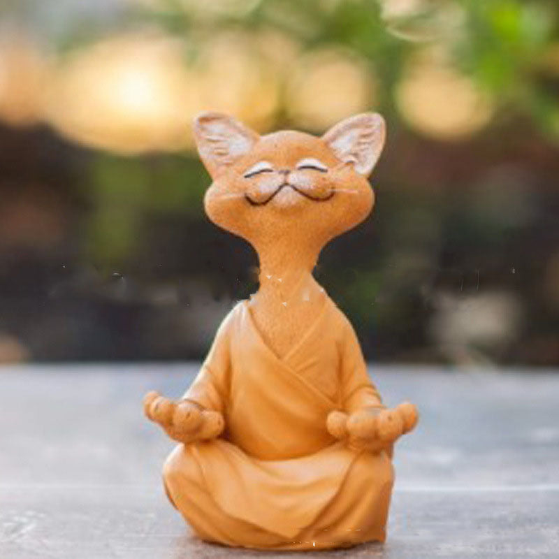 Cat-shaped figurine in a meditative pose on a reflective surface with a blurred natural background