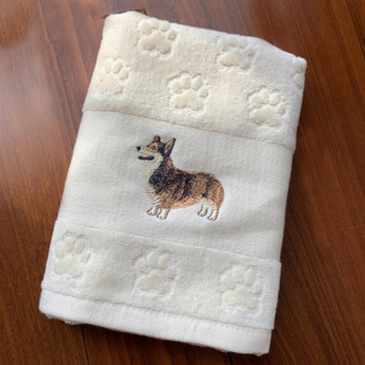 Folded towel with embroidered dog design on a wooden surface