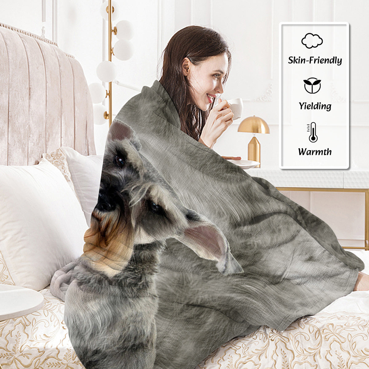 Woman wrapped in a gray blanket with a dog peeking out, in a cozy room.