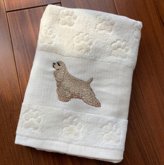 White towel with embroidered dog design on a wooden surface