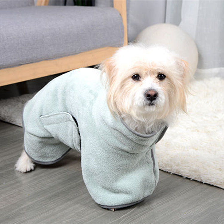 Small dog wearing a light blue fleece onesie on a wooden floor.
