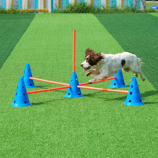 Dog running through an agility course with blue cones and orange bars on a green field.
