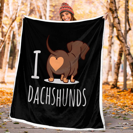Woman holding a black blanket with a dachshund design and 'I love dachshunds' text in an autumn setting.